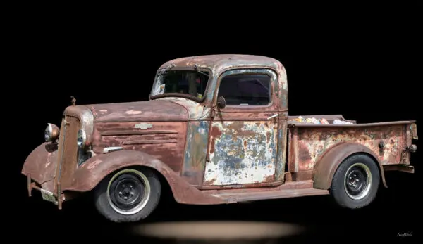 Rusty vintage pickup truck on black background.
