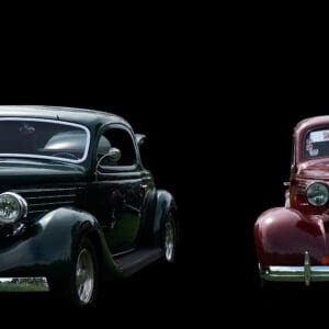 Two vintage cars on a black background.
